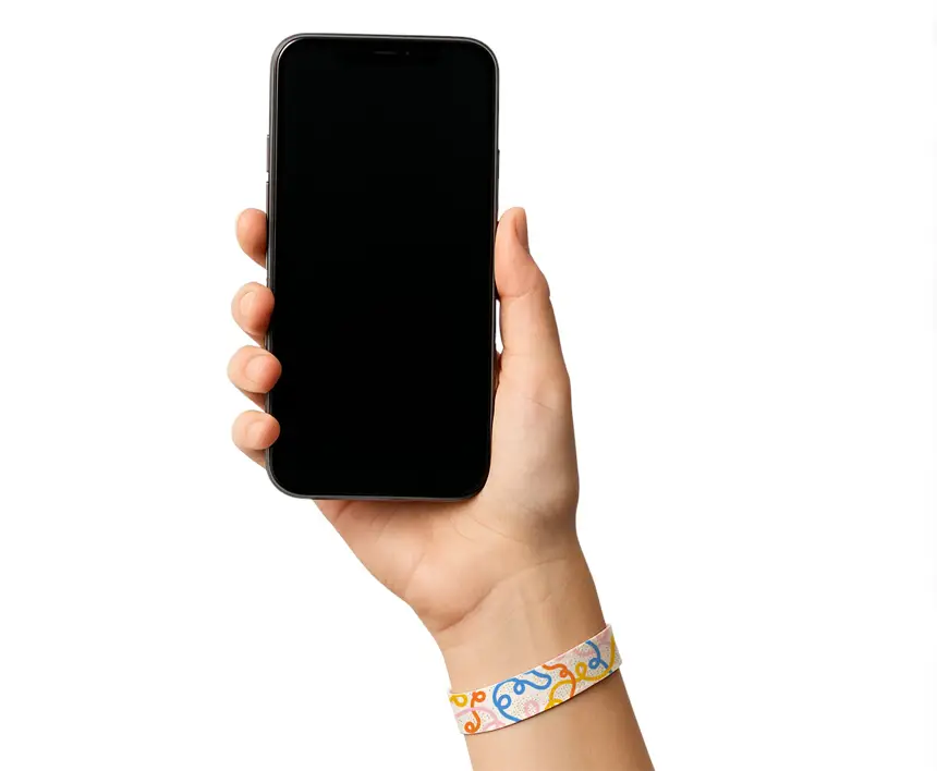 una mano de mujer con una pulsera de tela sosteniendo un teléfono móvil